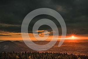 Sunset on JeÃÂ¡tÃâºd mountain with a TV transmitter next to Liberec. Heavy storm clouds push across the valley and a red sun peeks photo